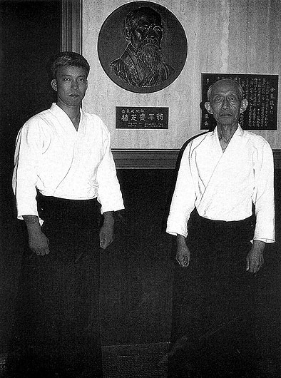 Глава айкидо Уэсиба киссёмару(ныне покойный) и Директор "Хамбу Додзё" Уэсиба Моритэру(нынешний Глава Айкидо) перед барельефом Основателя, в тренировочном Зале